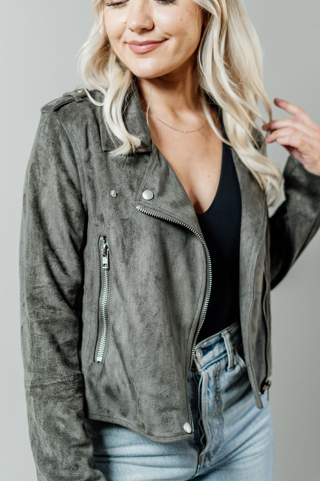 Pictured is a grunge-green, suede jacket with a moto-style collar, zipper closure, and side pockets with zippers.