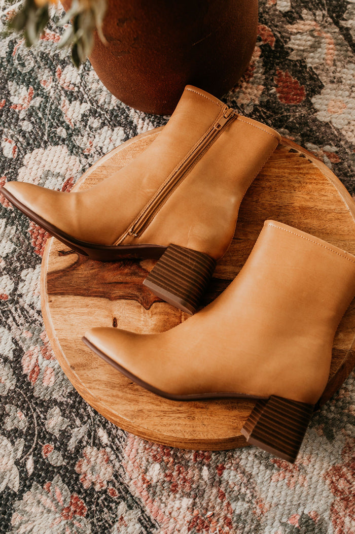 Pictured are brown heeled boots with a chunky heel, side zipper, and easy to clean material.