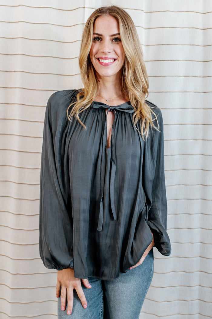 Steel blue blouse with flowy long sleeves and collar bow-tie on model.