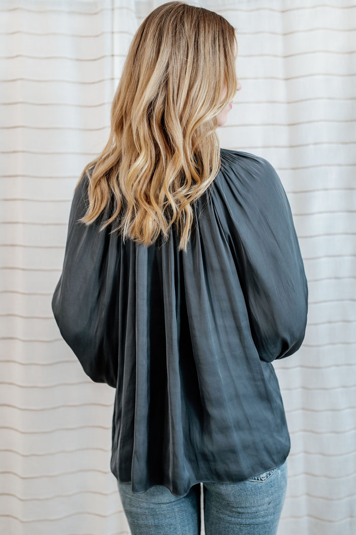 Steel blue blouse with flowy long sleeves and collar bow-tie on model.