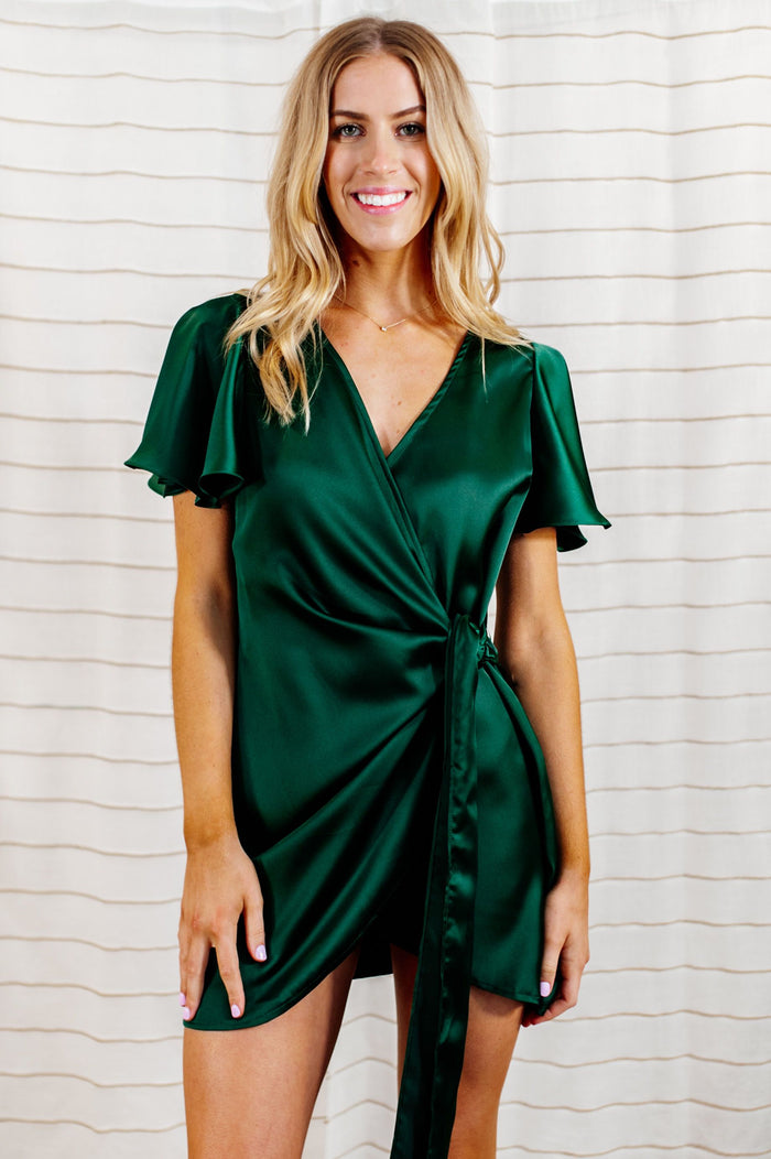 Pictured is a green, silky wrap dress with flowy sleeves and a wrap style body.