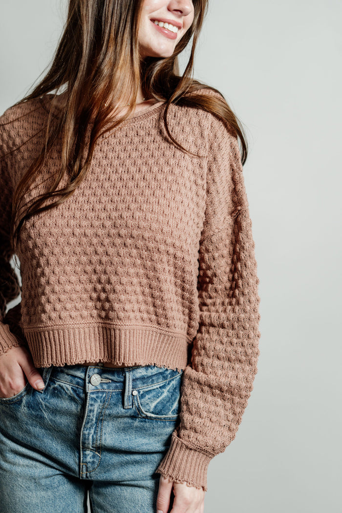 Pictured is a deep blush, knit sweater with a scoop neckline, cropped body, and cuffed knit sleeves.