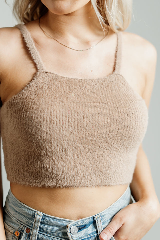 Pictured is a brown, knit top with fuzzy material, thin shoulder straps, and cropped body. 