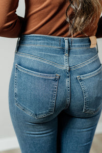 Pictured is a low-rise denim jean with a medium-wash, bootcut leg, and stretchy fit.