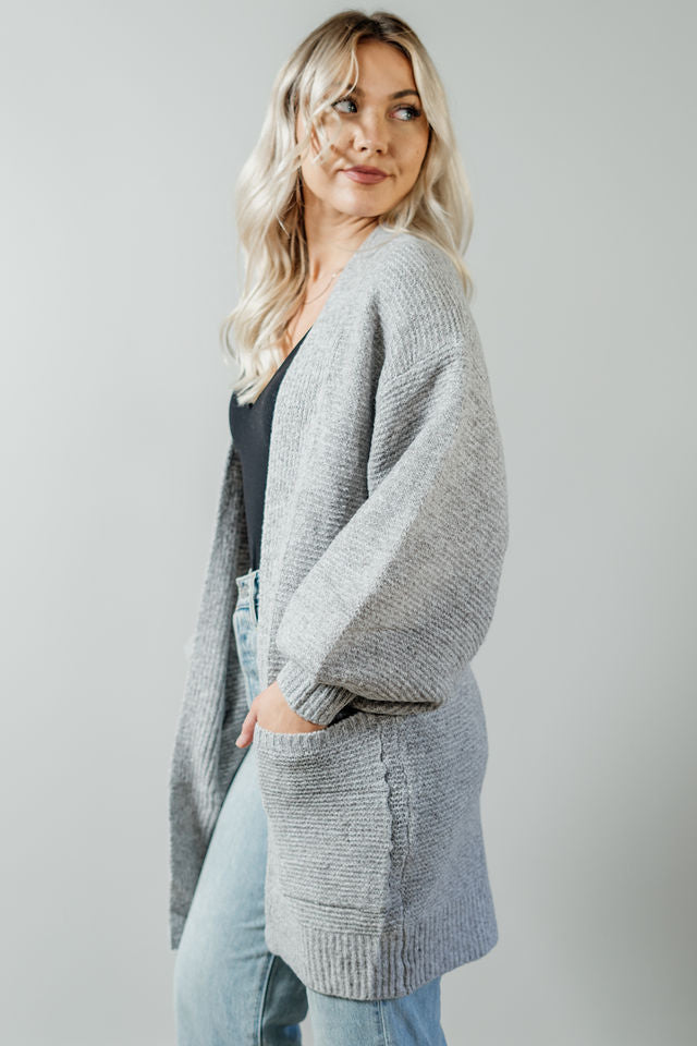 Pictured is a light grey, thick cardigan with balloon sleeves, long body, open front, and front pockets.