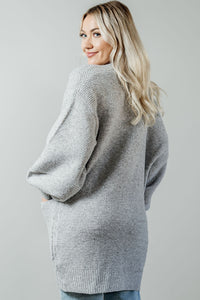 Pictured is a light grey, thick cardigan with balloon sleeves, long body, open front, and front pockets.