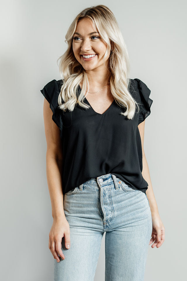 Pictured is a black, lightweight blouse with a v-neckline, ruffle cap sleeves, and flowy body. 