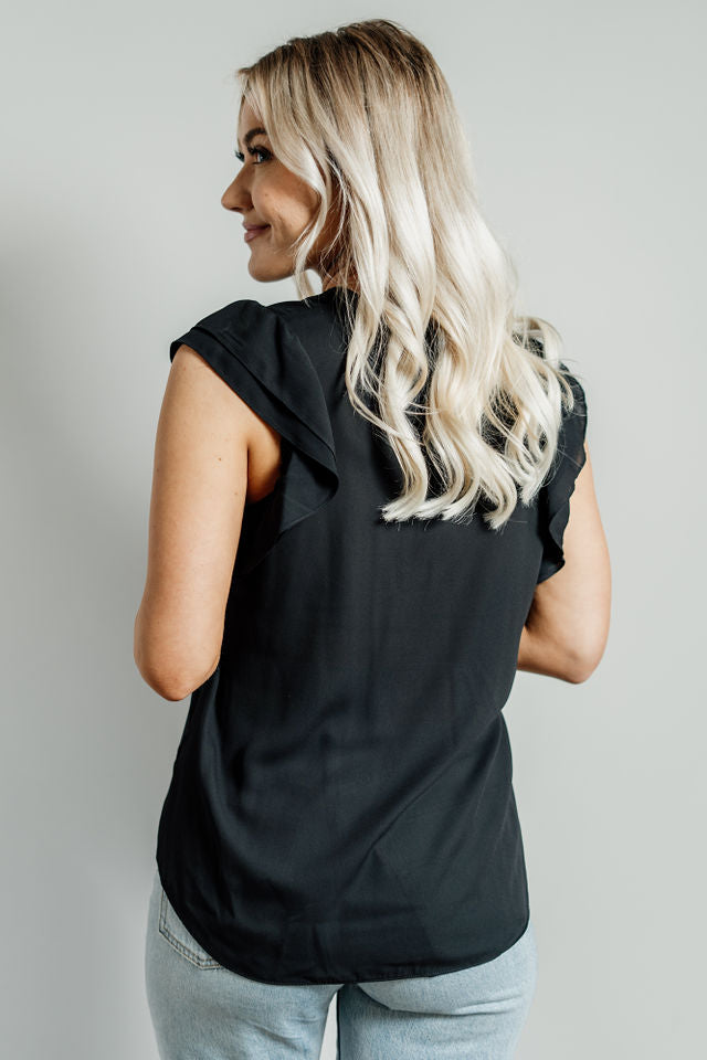 Pictured is a black, lightweight blouse with a v-neckline, ruffle cap sleeves, and flowy body. 