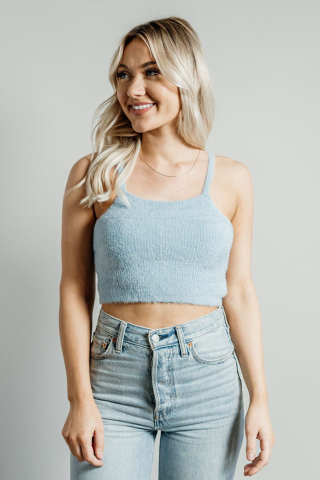 Pictured is a blue, knit top with fuzzy material, thin shoulder straps, and cropped body. 