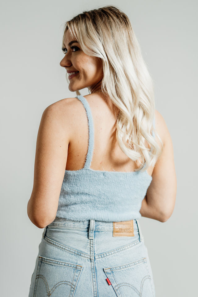 Pictured is a blue, knit top with fuzzy material, thin shoulder straps, and cropped body. 
