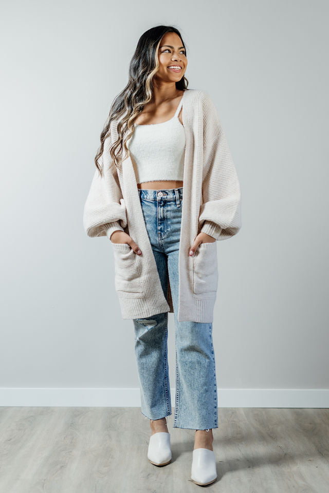 Pictured is a soft beige, thick cardigan with balloon sleeves, long body, open front, and front pockets.