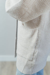 Pictured is a soft beige, thick cardigan with balloon sleeves, long body, open front, and front pockets.