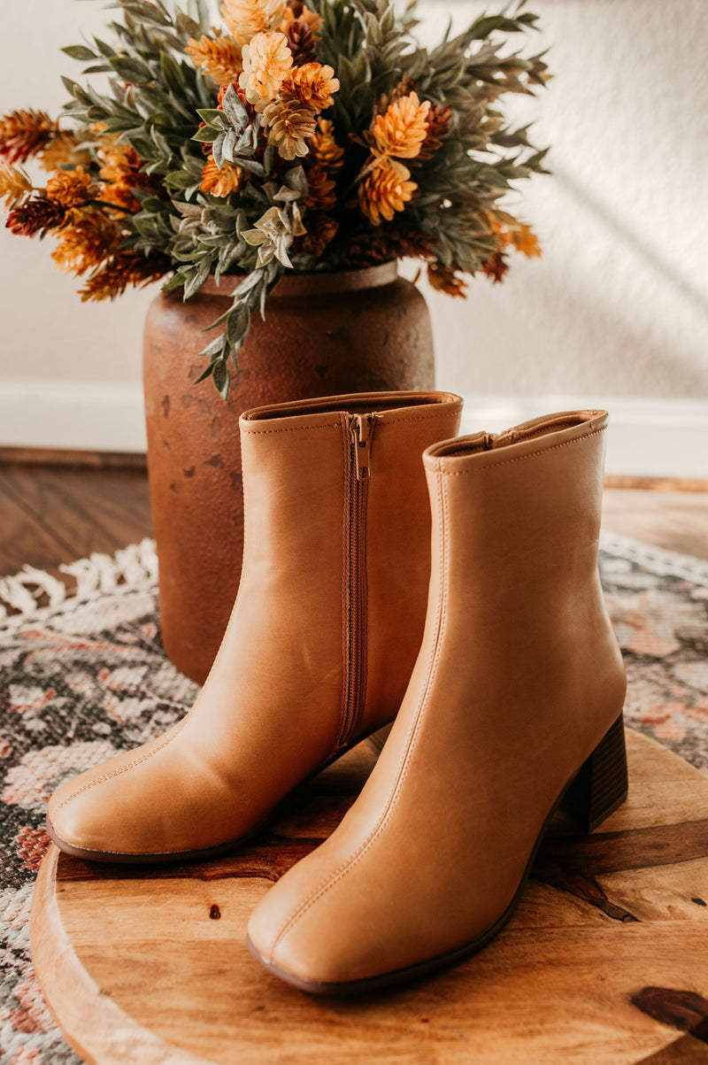 Pictured are brown heeled boots with a chunky heel, side zipper, and easy to clean material.