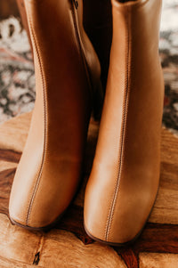 Pictured are brown heeled boots with a chunky heel, side zipper, and easy to clean material.