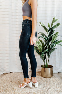 Pictured is a pair of dark-wash denim with a button fly, a high-rise waist, cropped ankles, and dark wash denim material.