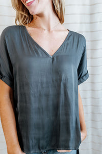 Gray colored blouse with cuffed sleeves and v-neck with flowy body on model.