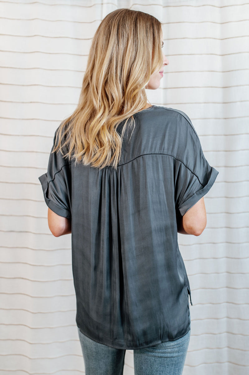 Gray colored blouse with cuffed sleeves and v-neck with flowy body on model.
