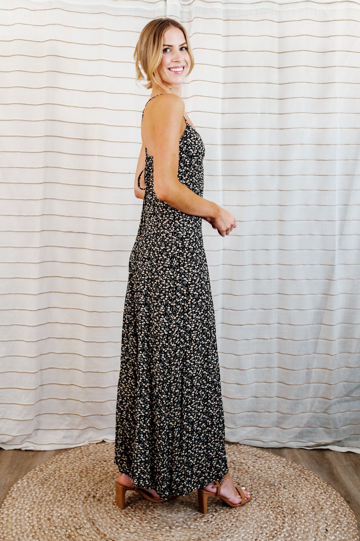 Pictured is a floral jumpsuit with a sweetheart bust, criss-cross shoulder ties, strappy open back, and wide-leg pants.