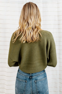 Pictured is a green jersey pullover with a plush knit material, cuffed sleeves, cropped body, and v-neckline.