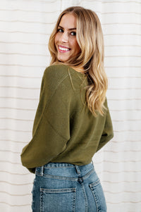 Pictured is a green jersey pullover with a plush knit material, cuffed sleeves, cropped body, and v-neckline.