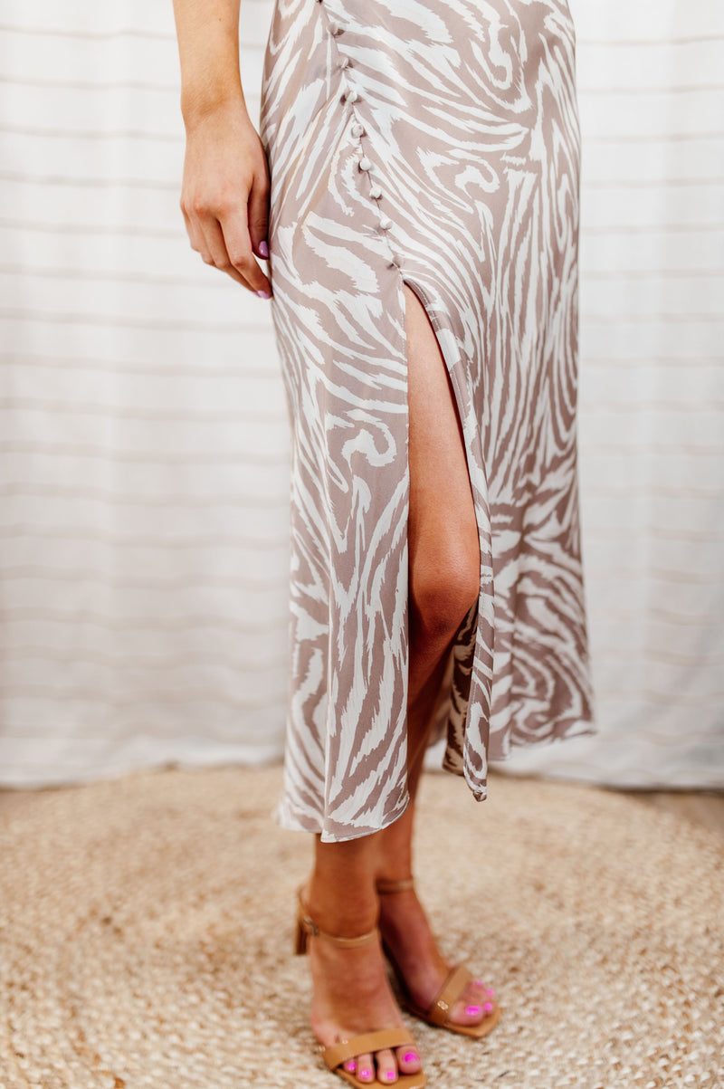 Pictured is a zebra print midi dress with adjustable straps, silky body, and mid length.
