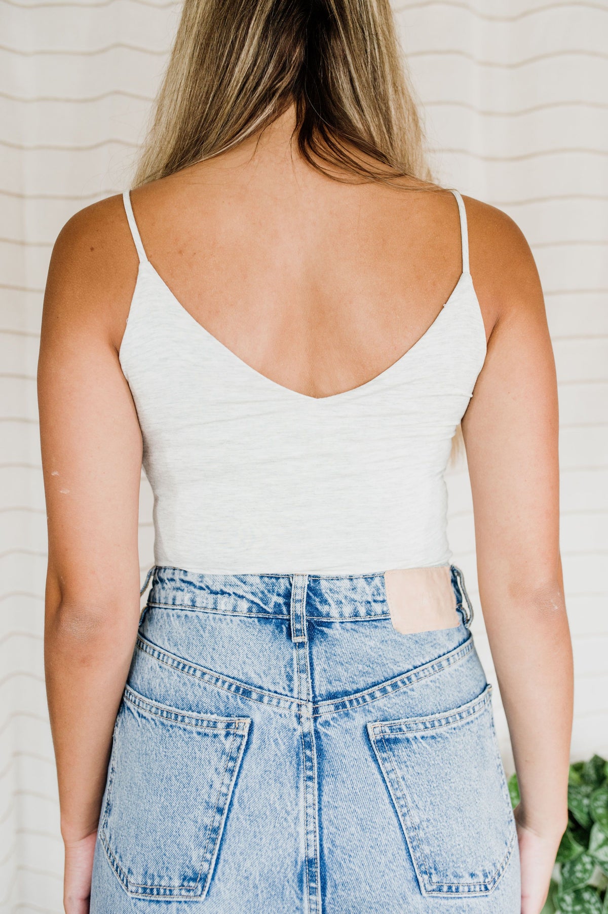 Pictured is a white tank with a soft fabric, spaghetti straps, and a v-neckline in the front and back. 