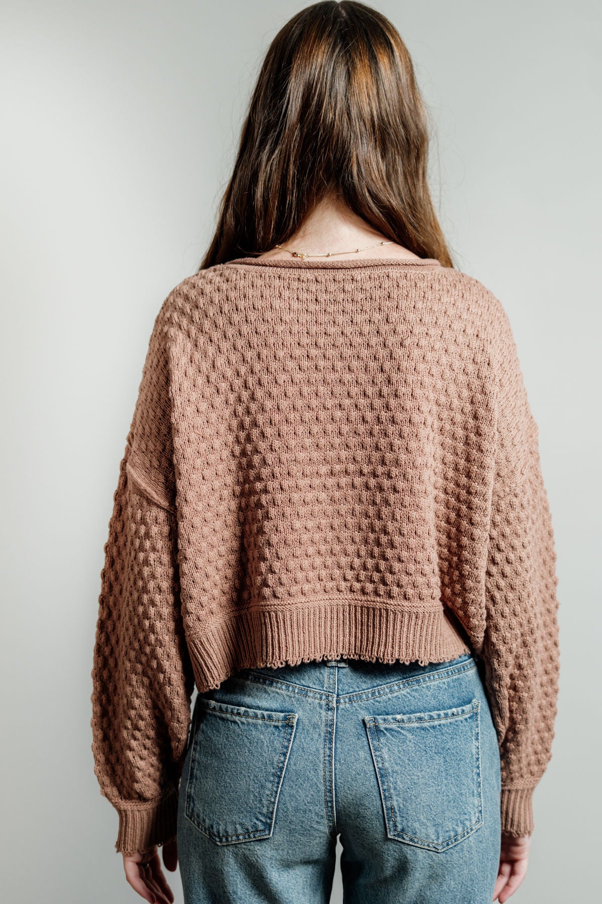 Pictured is a deep blush, knit sweater with a scoop neckline, cropped body, and cuffed knit sleeves.