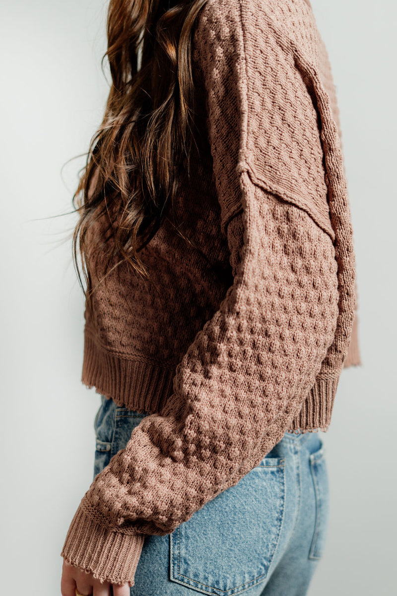 Pictured is a deep blush, knit sweater with a scoop neckline, cropped body, and cuffed knit sleeves.