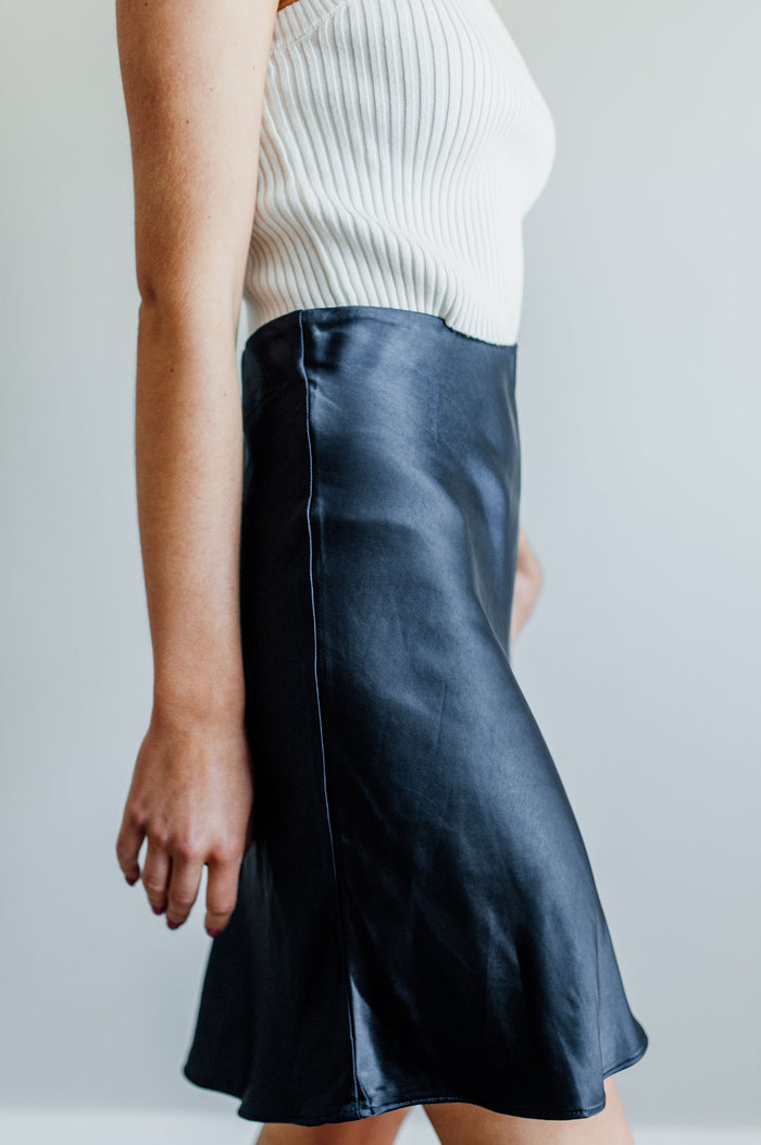 Pictured is a silky satin mini skirt with a fitted waist, slip style material, and flowy hem.