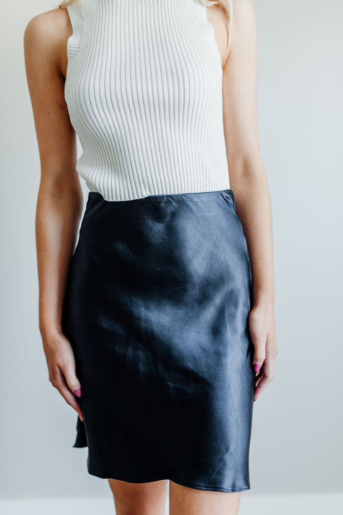 Pictured is a silky satin mini skirt with a fitted waist, slip style material, and flowy hem.