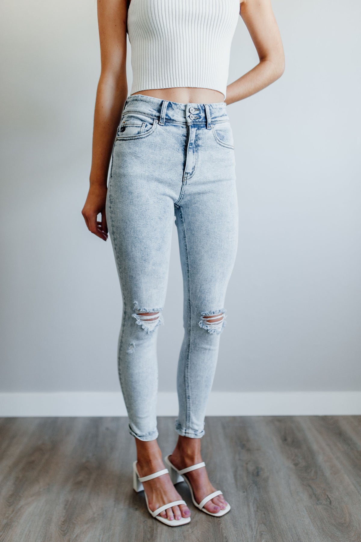 Pictured is a trendy high rise, denim jean with updated acid-wash material, light distressing, and cropped ankle.