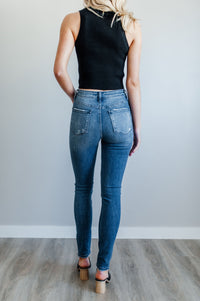 Pictured is a medium-wash, staple piece of denim with medium-rise waist, button fly, and cropped ankle with distressed hem.