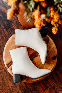 Pictured are white heeled boots with a chunky heel, side zipper, and easy to clean material.