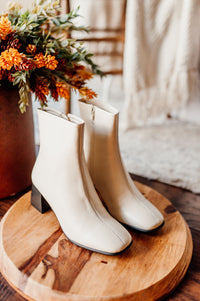 Pictured are white heeled boots with a chunky heel, side zipper, and easy to clean material.