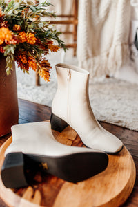 Pictured are white heeled boots with a chunky heel, side zipper, and easy to clean material.