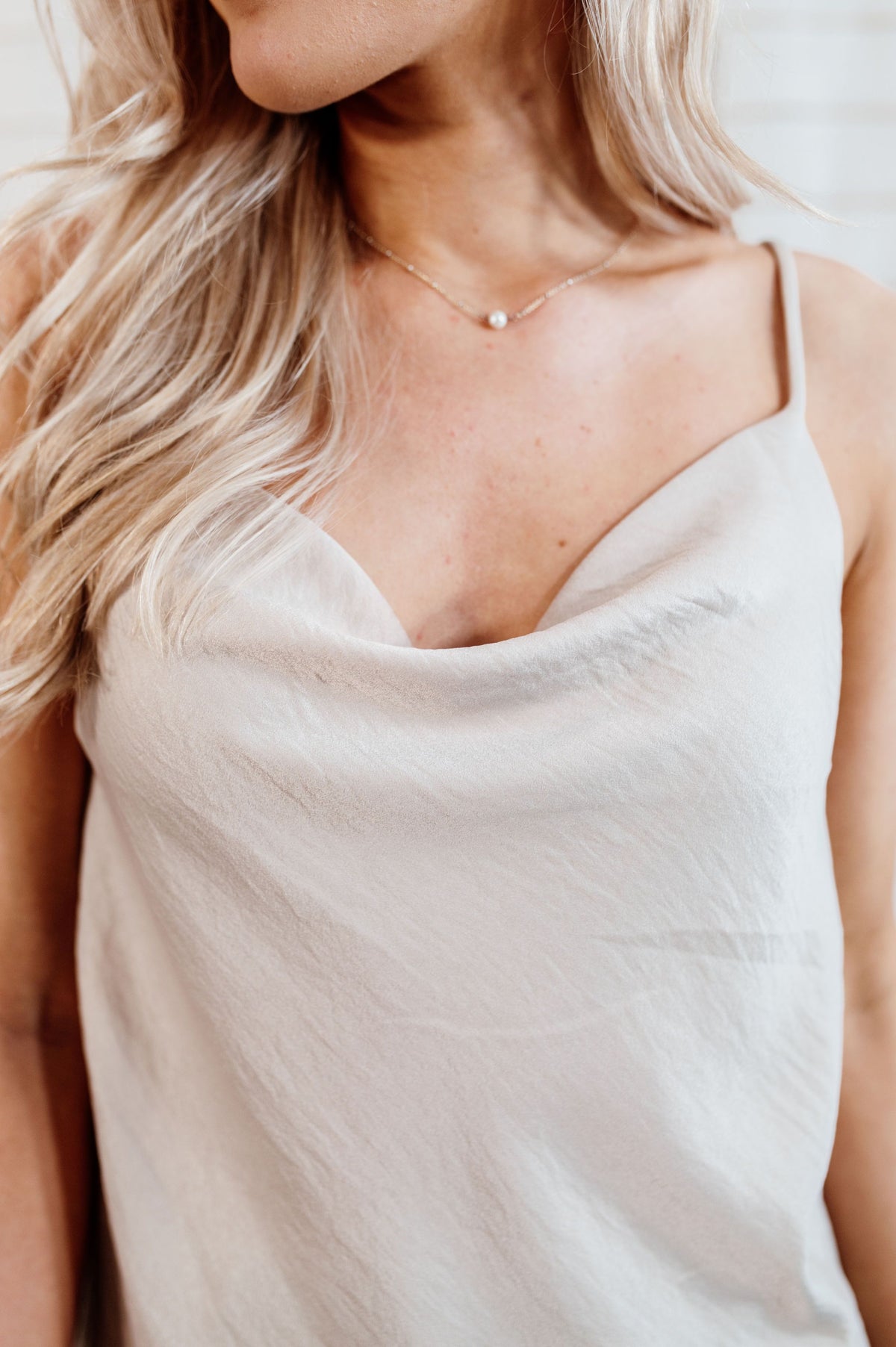 Oatmeal colored cowl neck tank top with flowy body on model.
