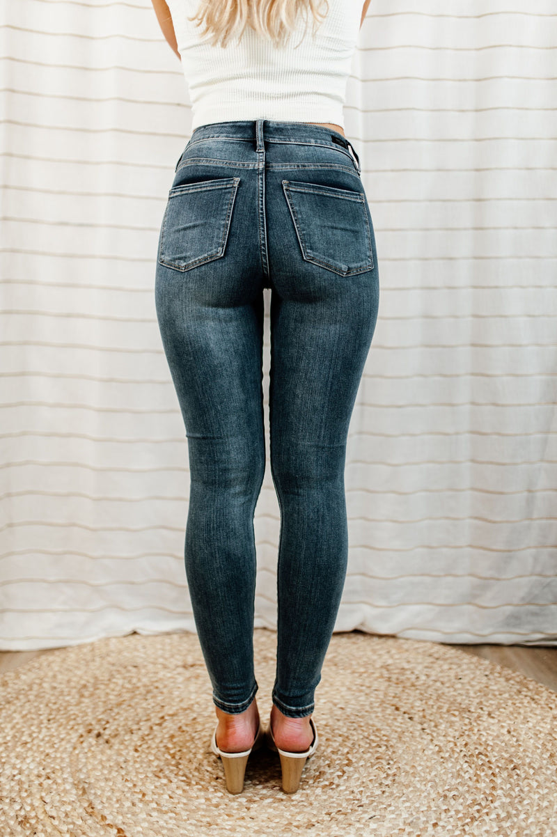 Dark-wash, mid-rise skinny jean with knee distressing on model.
