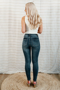 Dark-wash, mid-rise skinny jean with knee distressing on model.